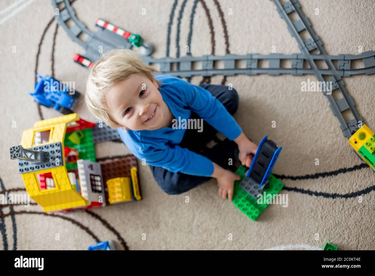 Adorable little boy playing with colorful plastic construction blocks ...