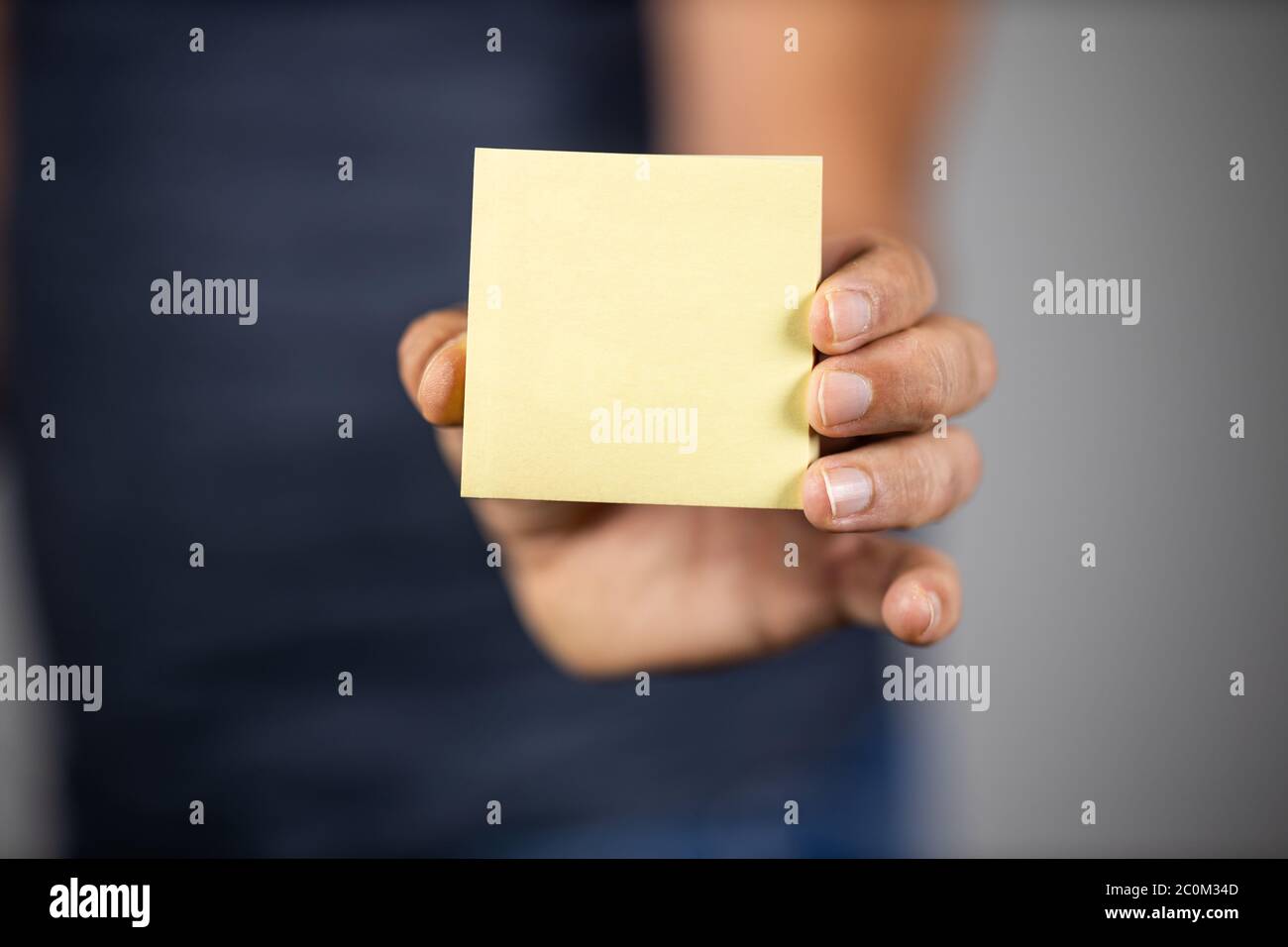 Man holding a yellow sticky note. Selective focus. Stock Photo