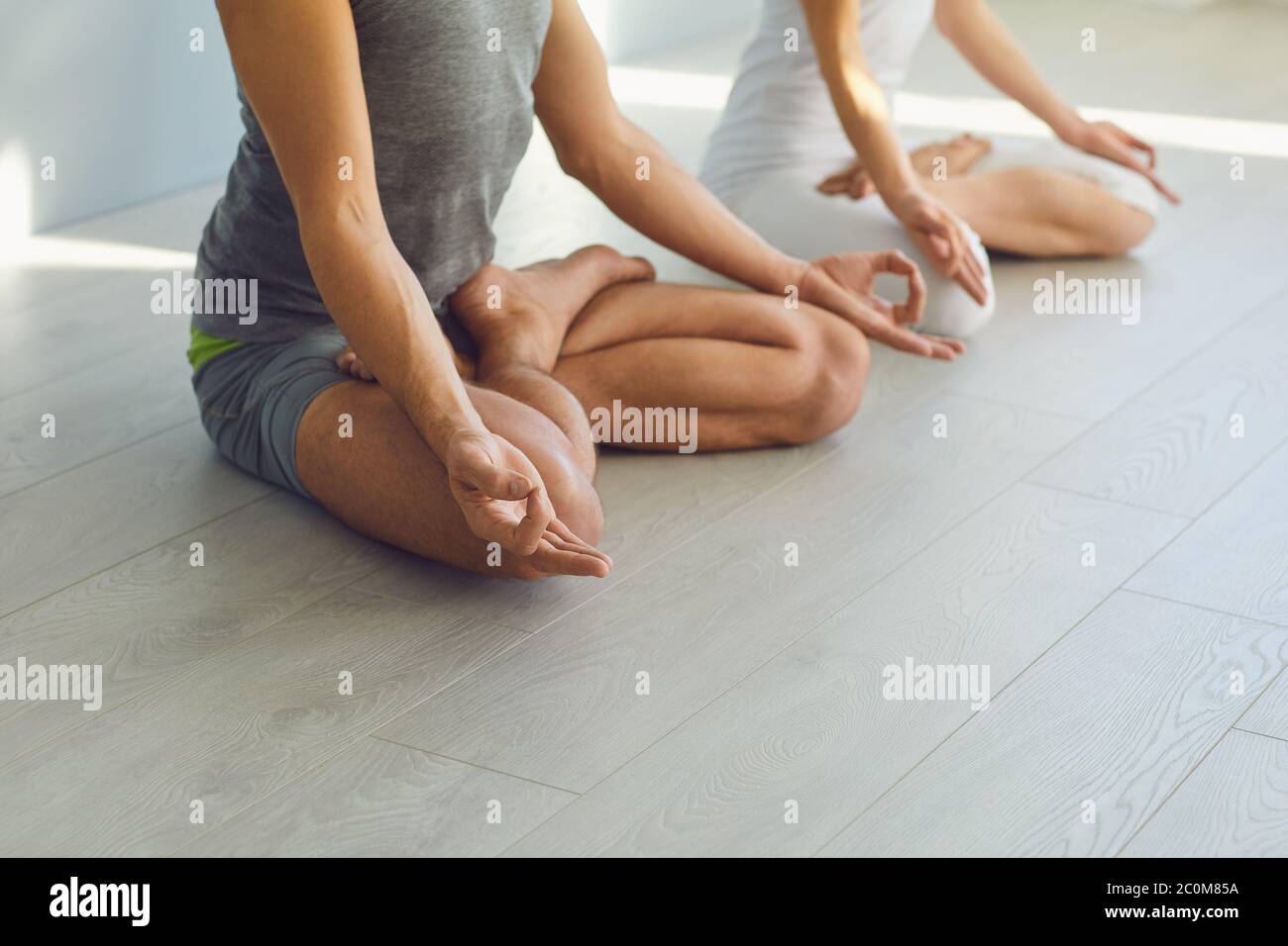 Close up of yoga couple people hand sitting relaxation in lotus field on floor in studio class. Stock Photo