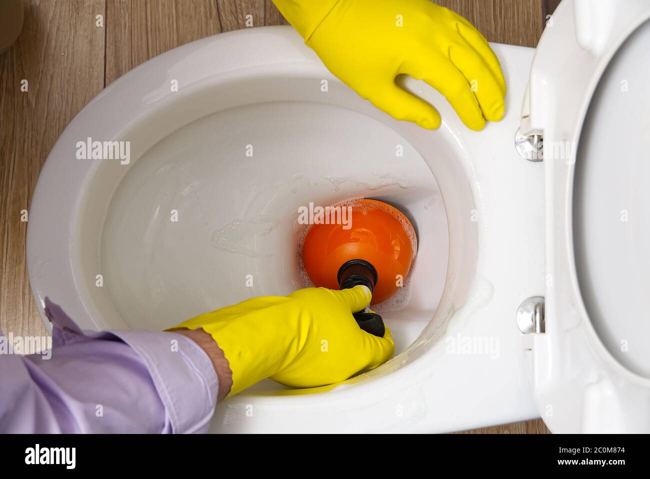 Man cleaning clogged toilet. broken overflowing toilet Stock Photo Alamy