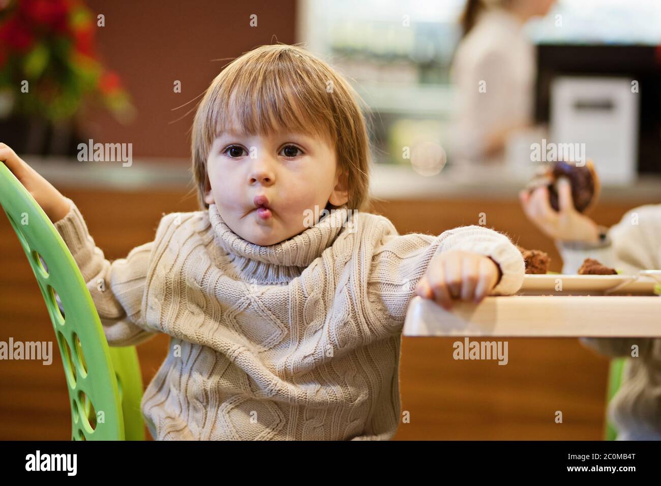 Little toddler boy, eating junk food in restaurant Stock Photo