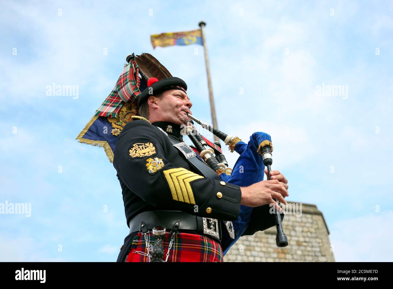 Her Majesty The Queen's Piper, Pipe Major Richard Grisdale, of The Royal Regiment of Scotland, on top of the Round Tower at Windsor Castle, joining pipers and musicians in marking the Battle of St Valery-en-Caux, where he played the pipers' march Heroes of St Valery to commemorate the thousands of Scots who were killed or captured during "the forgotten Dunkirk" 80 years ago. Stock Photo