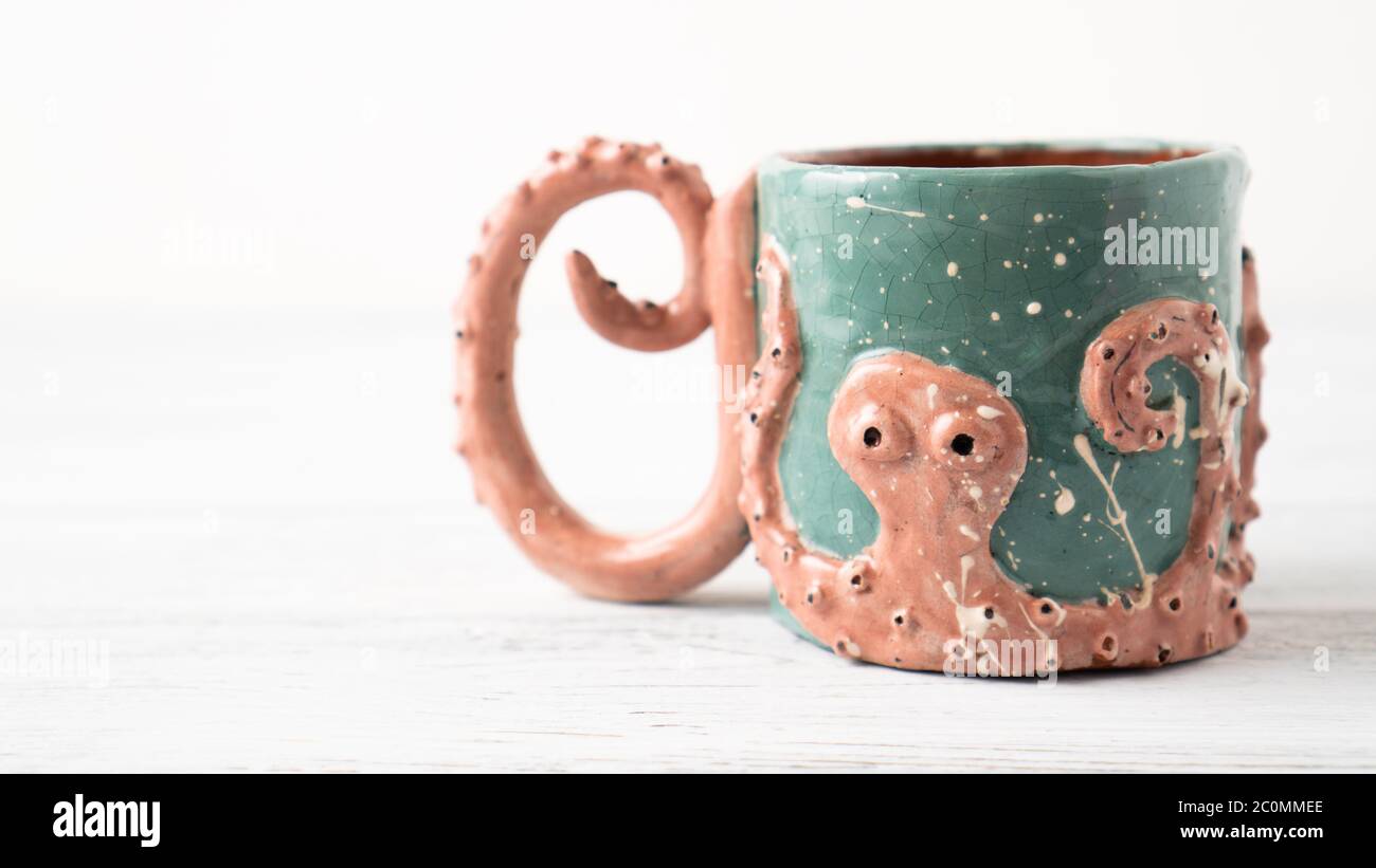 Self made Kraken mug. Clay cup. Original cup as a gift. Mug for children. Octopus crafts. Personalized mug. Coffee cup. Stock Photo