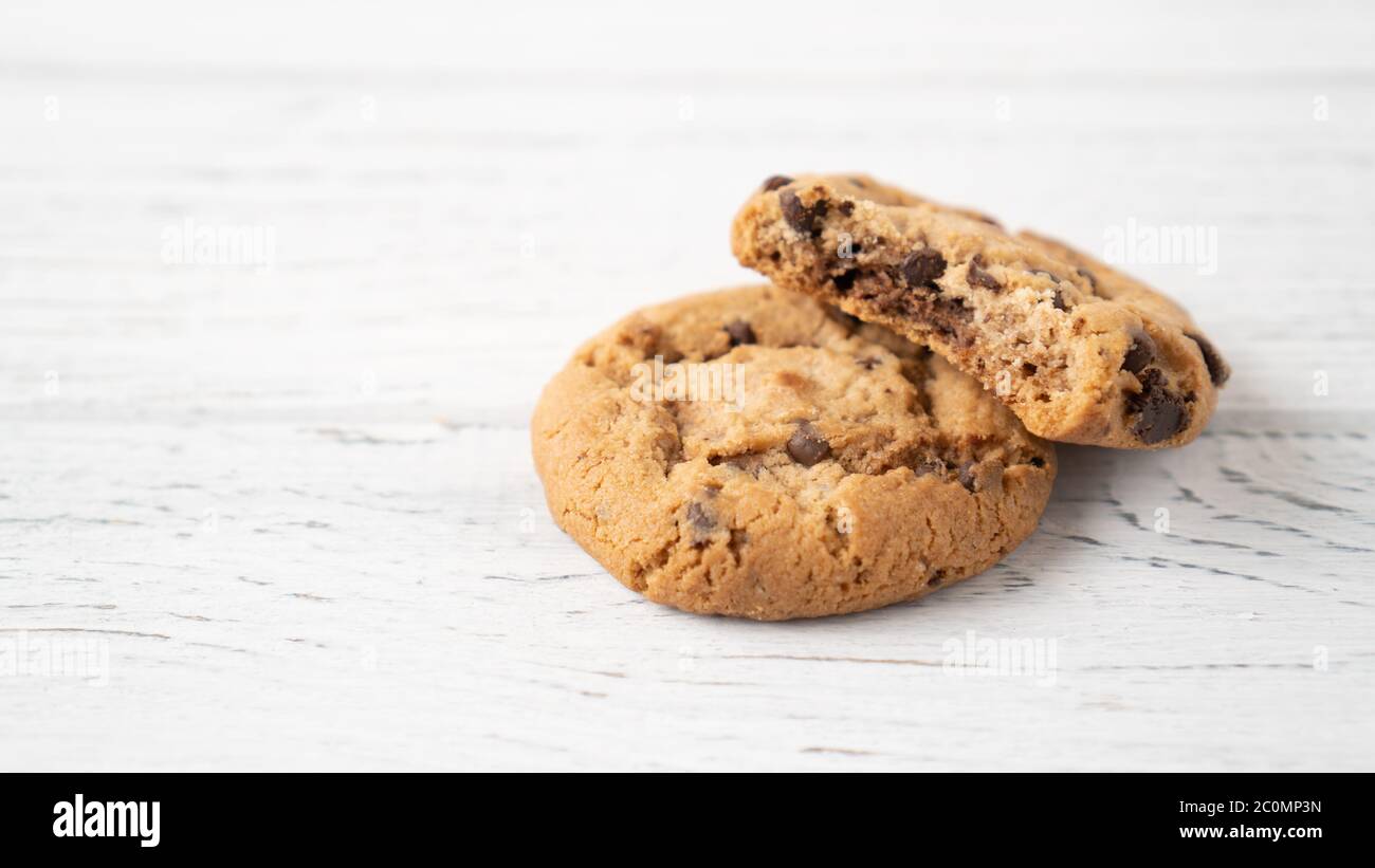 Bitten chocolate chip cookie. Two cookies with chocolate drops on white wooden table. place for message. Isolated Stock Photo