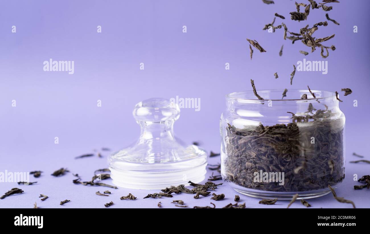Large leaf black tea in glass jar. Flying tea leaves. Falling dried ...