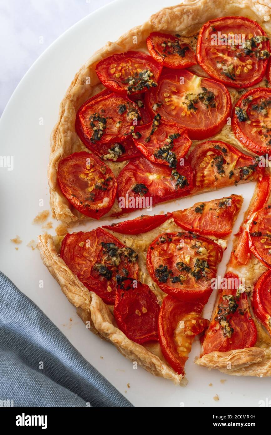 Tomato and mustard tart with cut slice on a large white plate Stock Photo