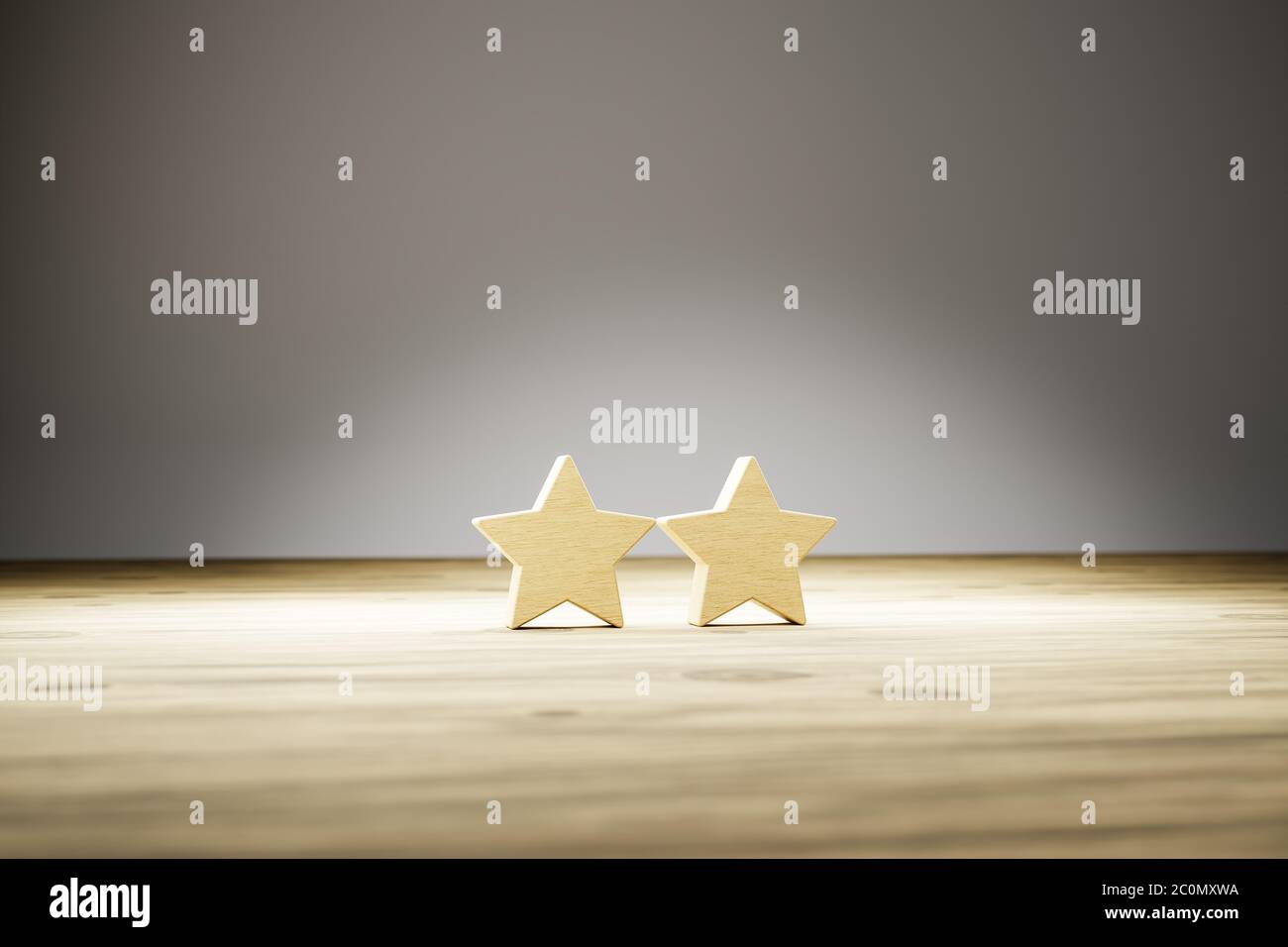 Two star rating: two wooden stars in a row on a wooden table with gray background. Selective focus. Concept shot for rating / reviews. Stock Photo