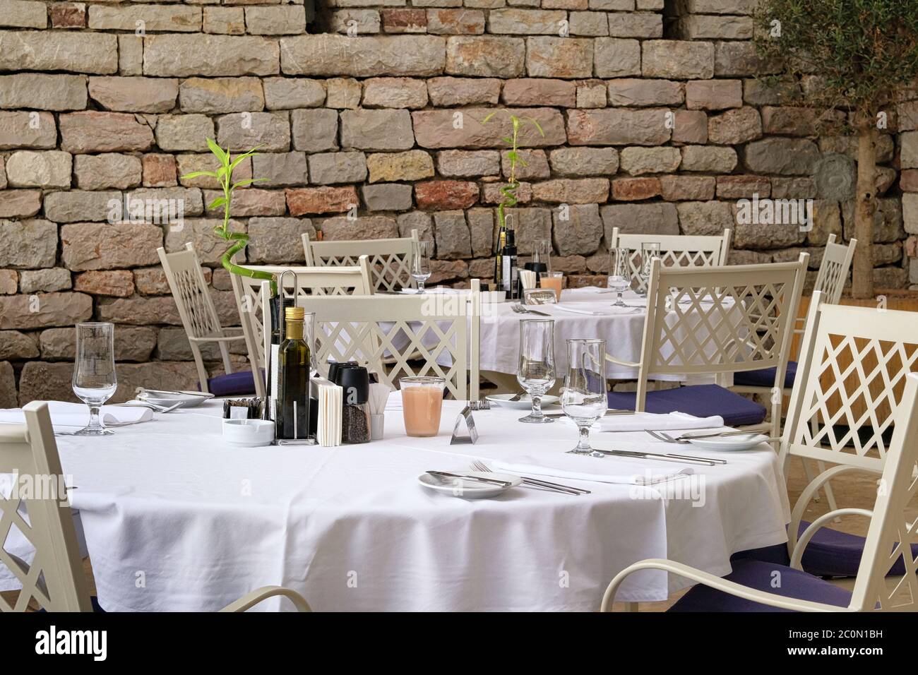 Table setting in modern restaurant. Decorated holiday table on outdoor terrace of cafe. Patio in suny summer in recreation. Stock Photo