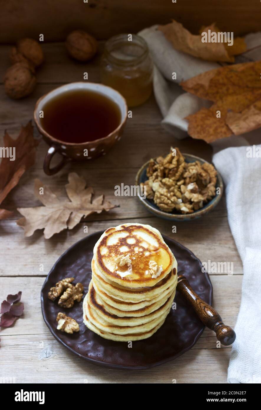 Vegetarian breakfast of fritters with honey, nuts and tea. Autumn still life. Stock Photo