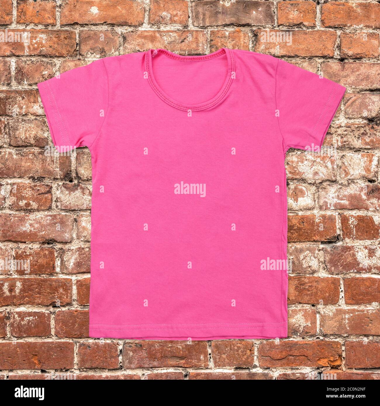 Pink blank t-shirt on dark brick background Stock Photo