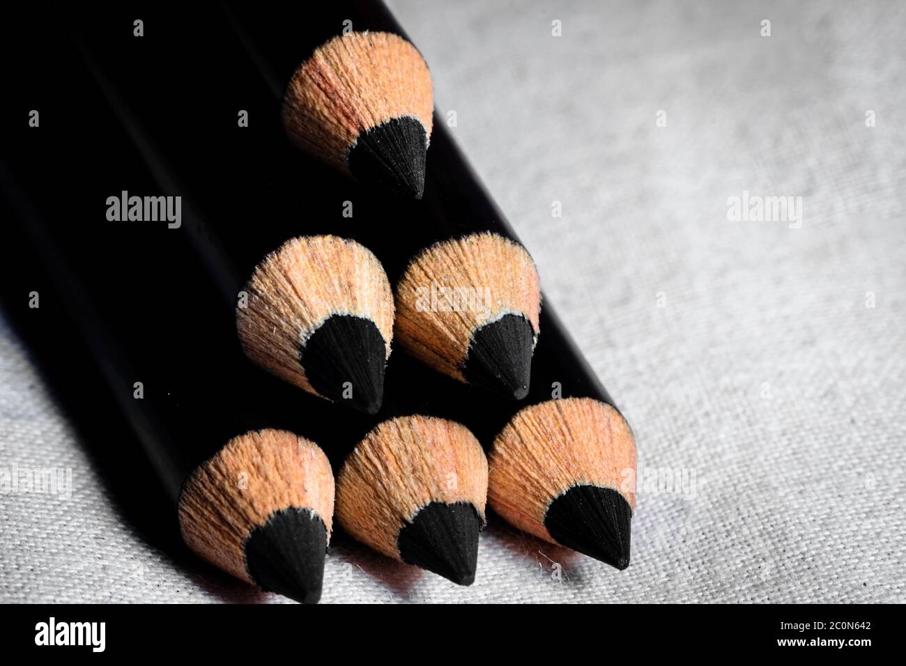 A group of pencils are kept one over another to make the shape of a triangle and focus on the tips. Side view Stock Photo