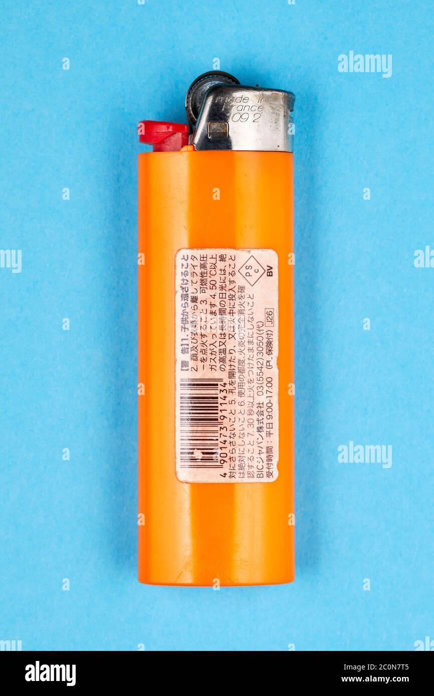 Orange plastic lighter (Bic), backside sticker with Japanese text, on blue  background Stock Photo - Alamy
