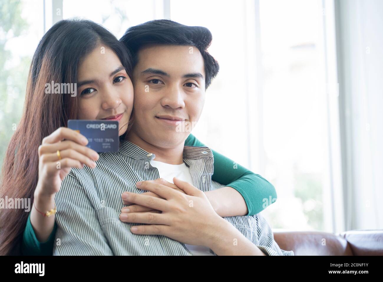 Couples help each other online shopping with credit cards. Stock Photo