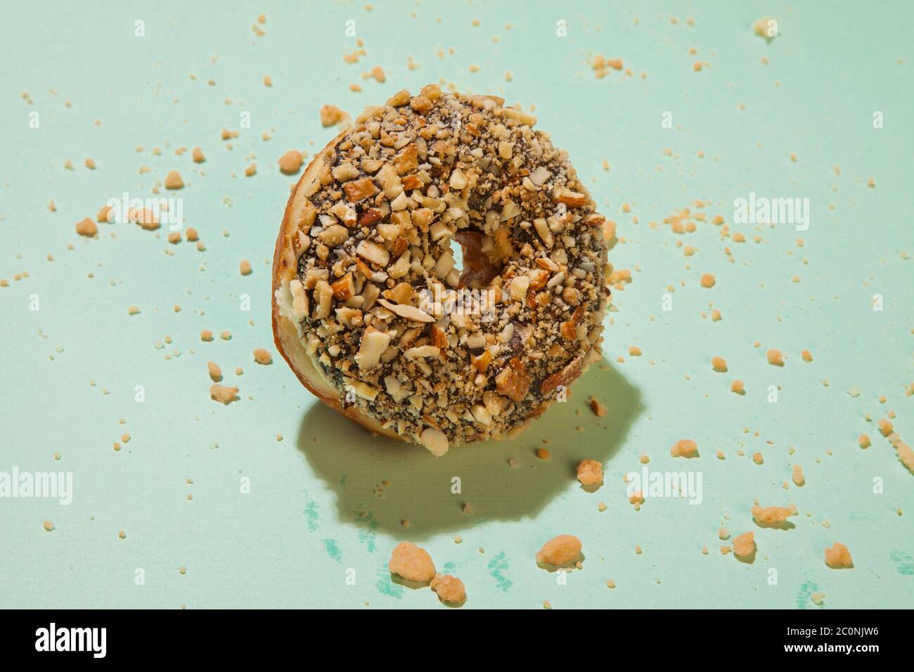 Chocolate doughnut with nuts topping on green background Stock Photo