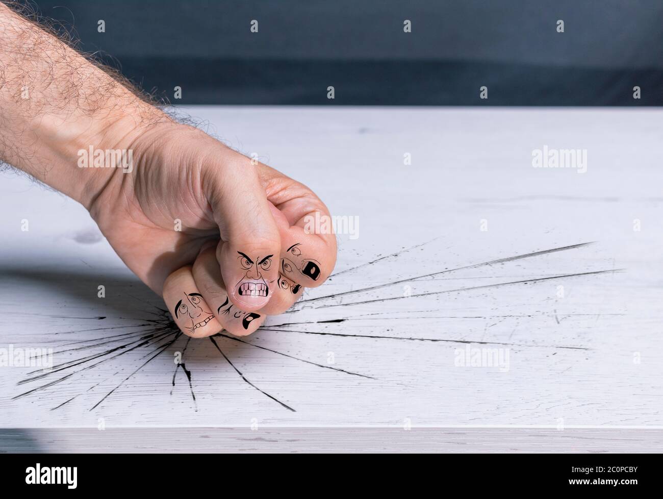 Fist hitting table with violence, with cartoons on the fingers simulating bullying, male violence, gender violence and domination Stock Photo