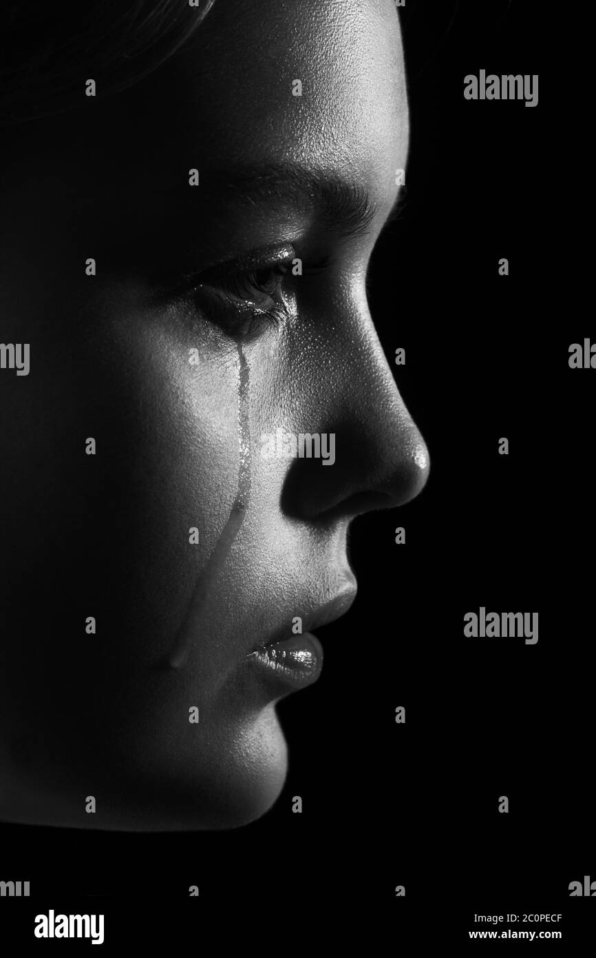 sad woman crying, looking aside on black background, closeup portrait, profile view, monochrome Stock Photo