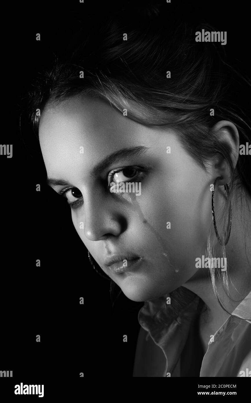sad woman crying, looking at camera on black background, closeup portrait, monochrome Stock Photo