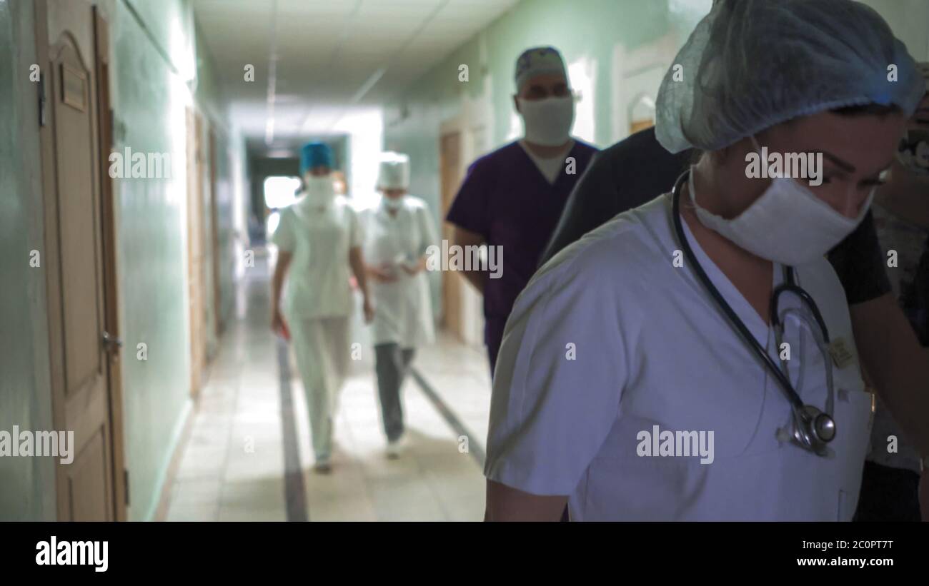 Medical team walking together along hospital corridor. Group of doctors in hurry for surgery or for examination of patients. Abstract defocused image Stock Photo