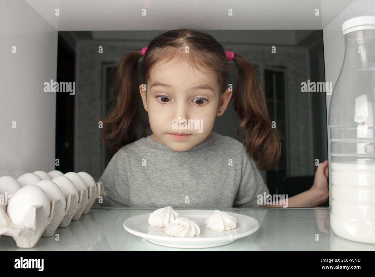 View from refrigerator, joyful funny child girl found cakes Stock Photo