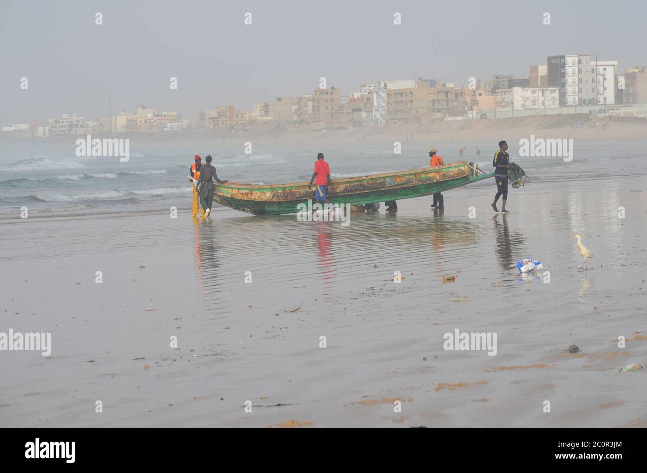 A group of artisanal fishers pushing a pirogue in Yoff beach, Dakar, Senegal Stock Photo