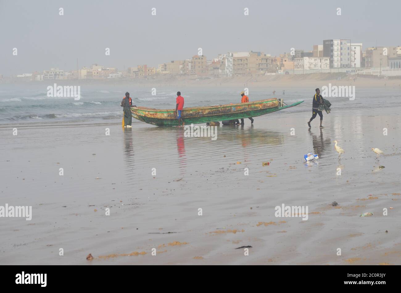 A group of artisanal fishers pushing a pirogue in Yoff beach, Dakar, Senegal Stock Photo