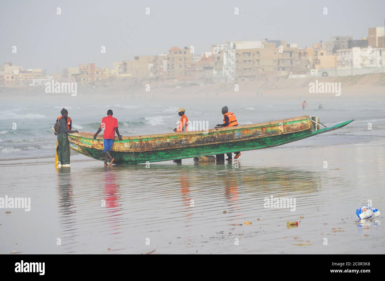 A group of artisanal fishers pushing a pirogue in Yoff beach, Dakar, Senegal Stock Photo