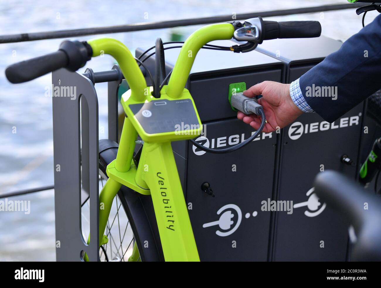 12 June 2020, Thuringia, Saalburg-Ebersdorf: Hannes Neupert from EnergyBus GmbH places an e-bike at the new e-bike charging station, which was put into operation the same day at the Fahrgastschifffahrt Saalburg. Further stations are to follow in order to boost cycle tourism in the reservoir region known as the 'Thuringian Sea' at the Bleiloch Dam and the Hohenwarte Reservoir. Photo: Martin Schutt/dpa-Zentralbild/dpa Stock Photo