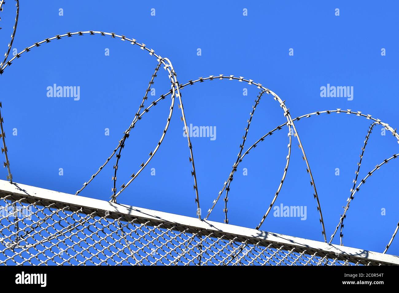 Fence with a barbed wire against the blue sky Stock Photo - Alamy