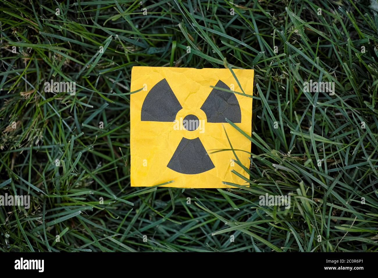Radiation warning sign on a green grass. Close up. Stock Photo