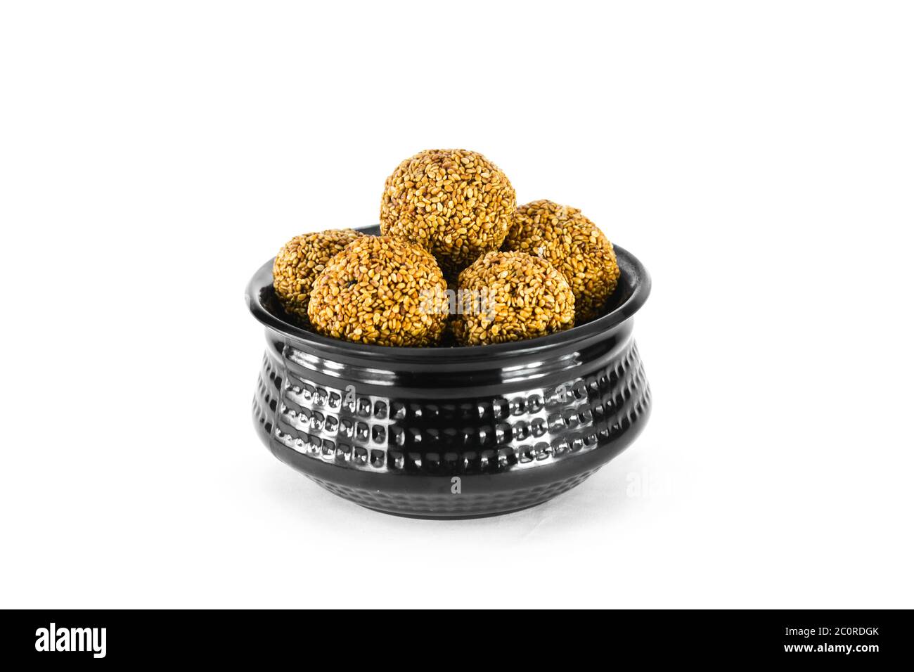 Sesame seed ball or tilgul laddo in black bowl isolated on white