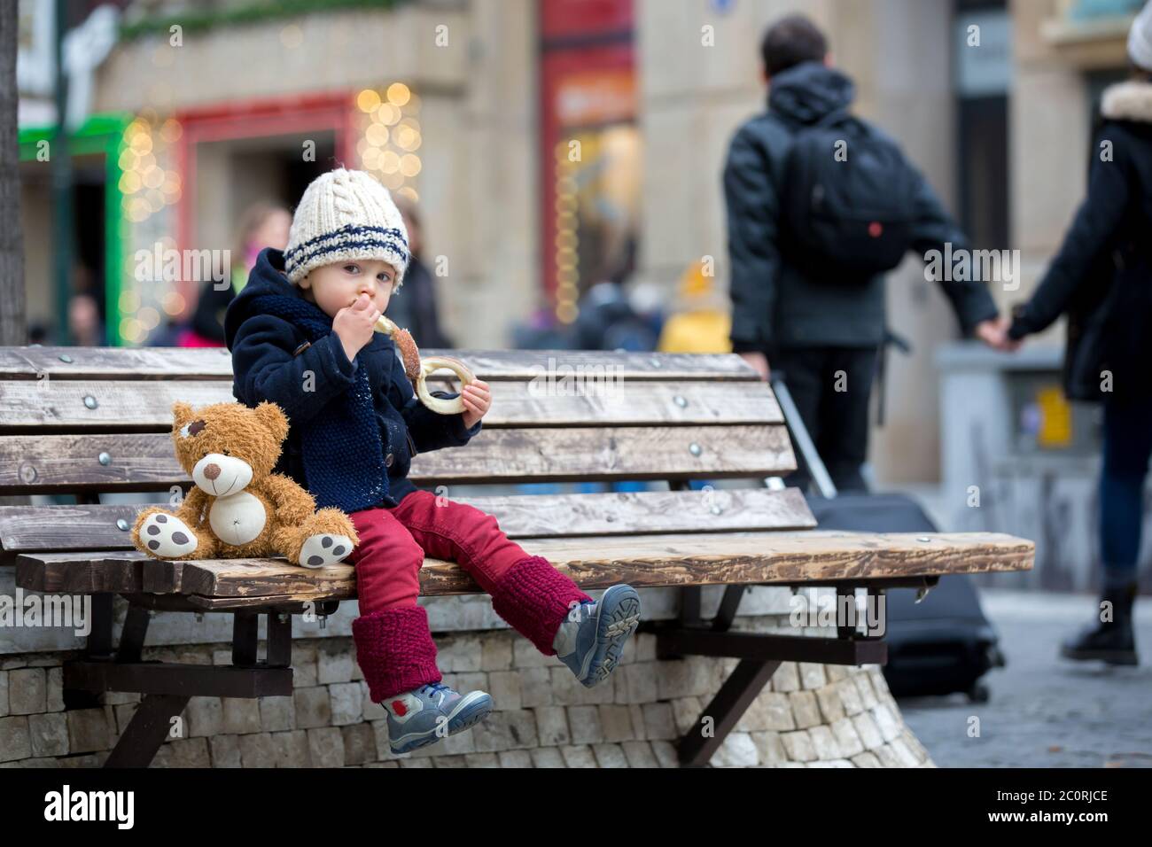 Fashion Toddler Boy With Teddy Bear Toy Eating Traditional Czech Sweet Pastry Called Trdlo In The City Center Sitting On Bench Christmas Time Stock Photo Alamy