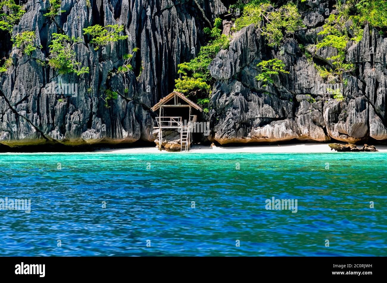 Lonely wooden bamboo house on stilts at a small hidden beach of rocky island Stock Photo