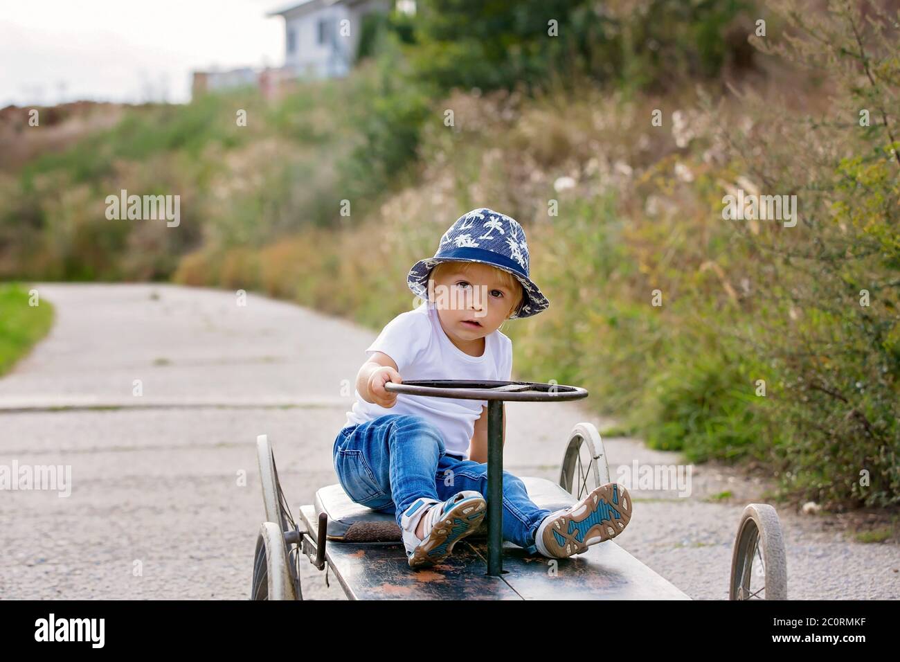 Adorable toddler boy, riding old retro car with four wheels in a