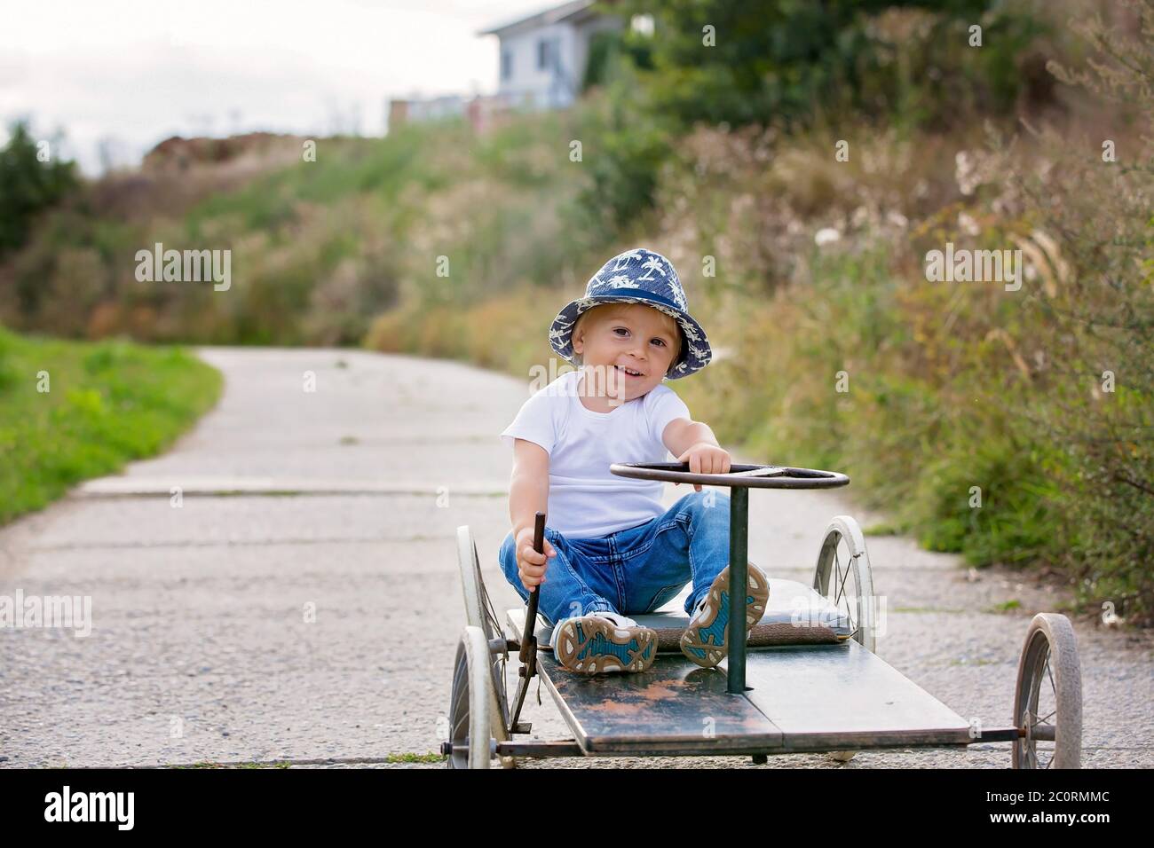 Adorable toddler boy, riding old retro car with four wheels in a