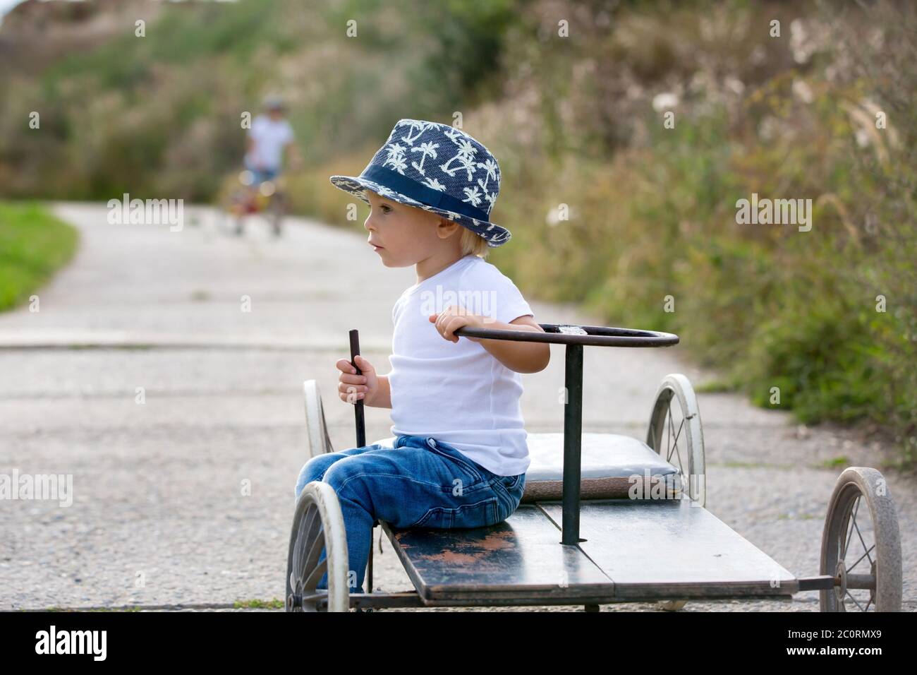 Adorable toddler boy, riding old retro car with four wheels in a village Stock Photo