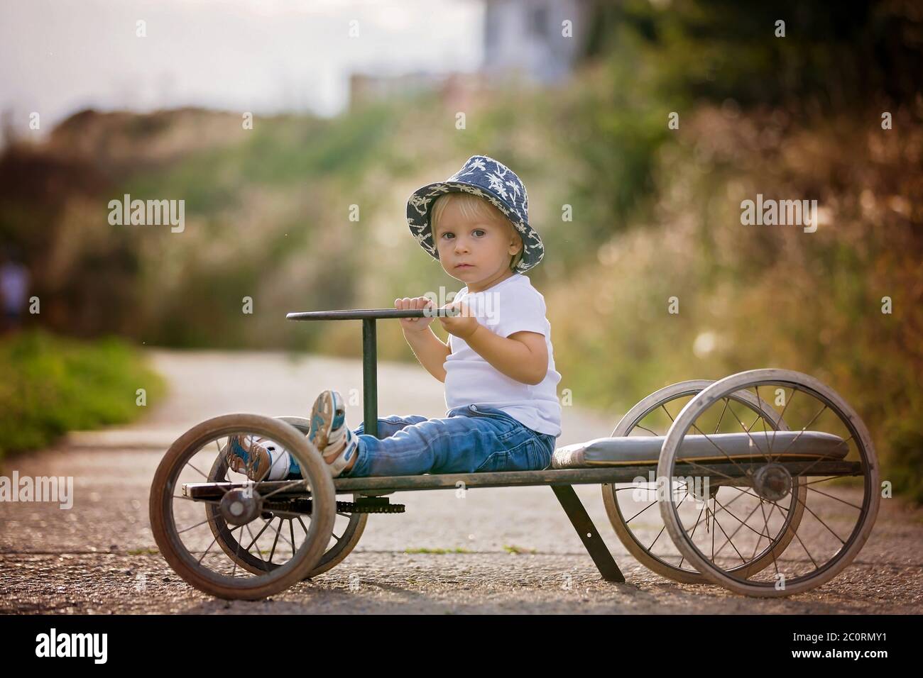 Adorable toddler boy, riding old retro car with four wheels in a