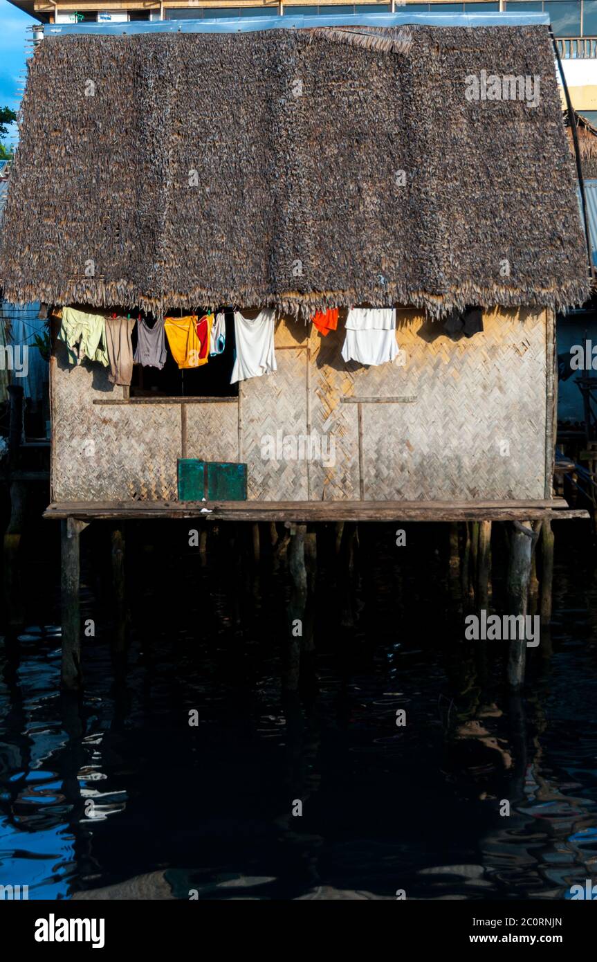 Small Nipa wooden House with close hanging out the window on stilts and Water Stock Photo
