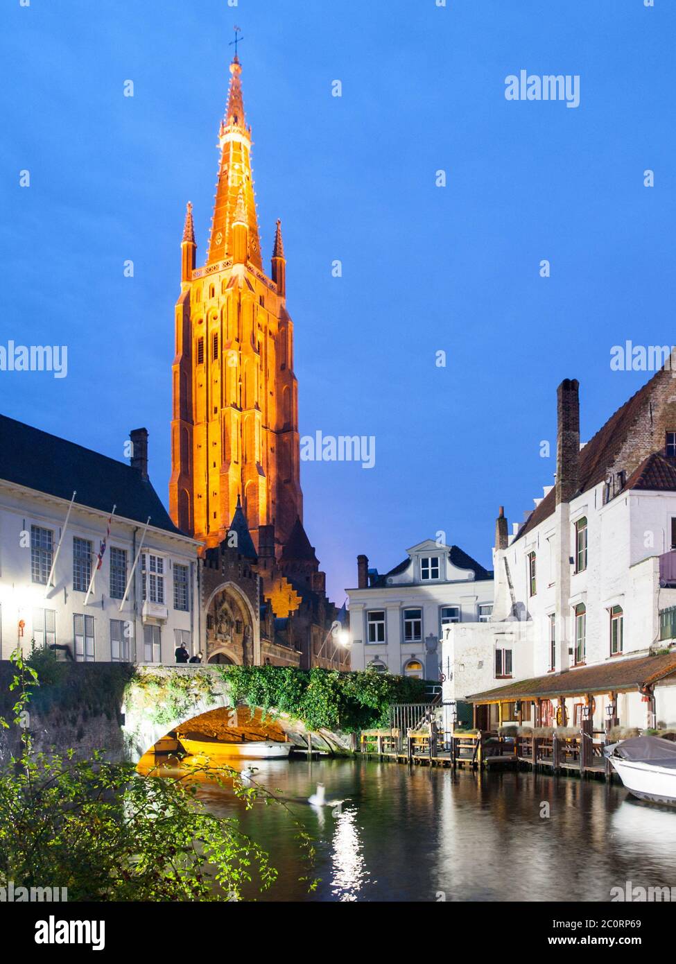 Church of Our Lady and bridge over water canal by night, Bruges, Belgium. Stock Photo