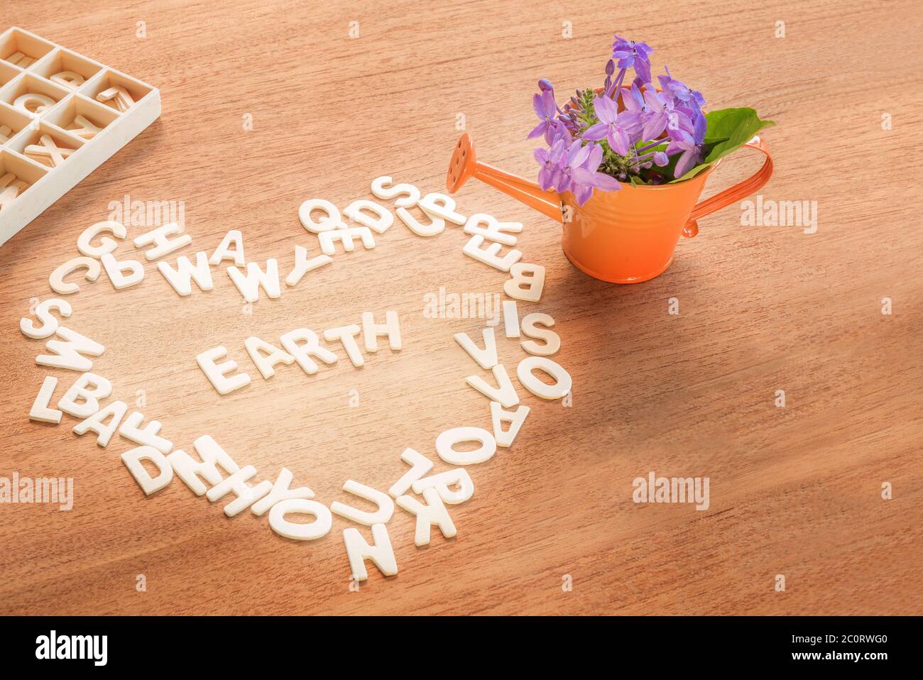 love and save the world concept, wooden alphabet formed heart shape with the word earth inside anda  watering can with flowers on a wood table backgro Stock Photo