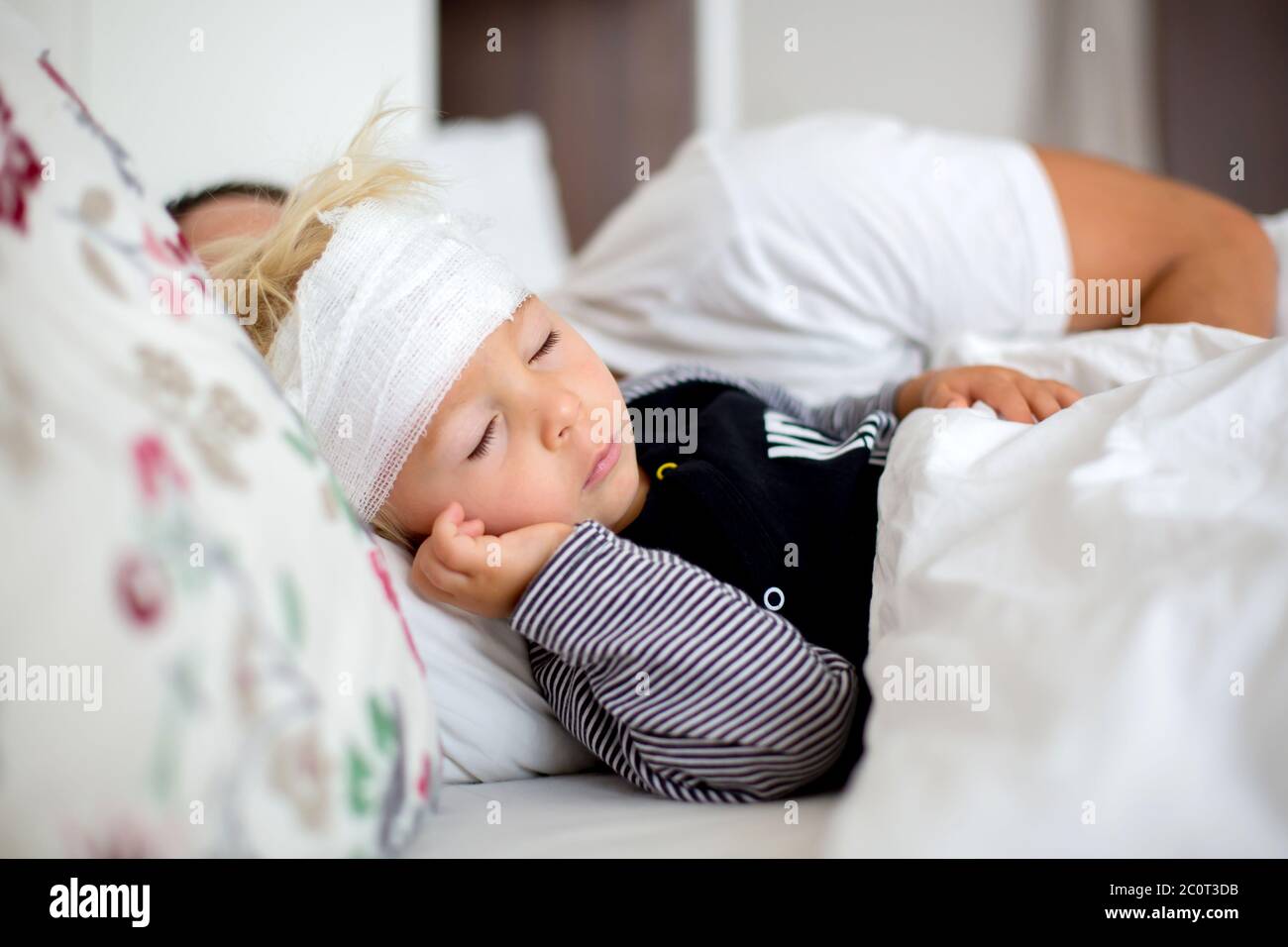 Little toddler boy with head injury, lying in bed, tired, sleeping