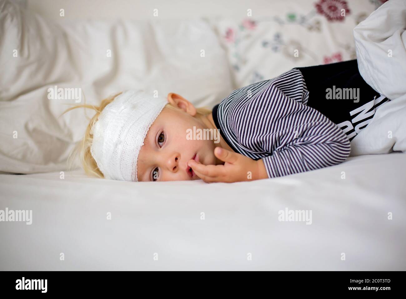Little toddler boy with head injury, lying in bed, tired, sleeping