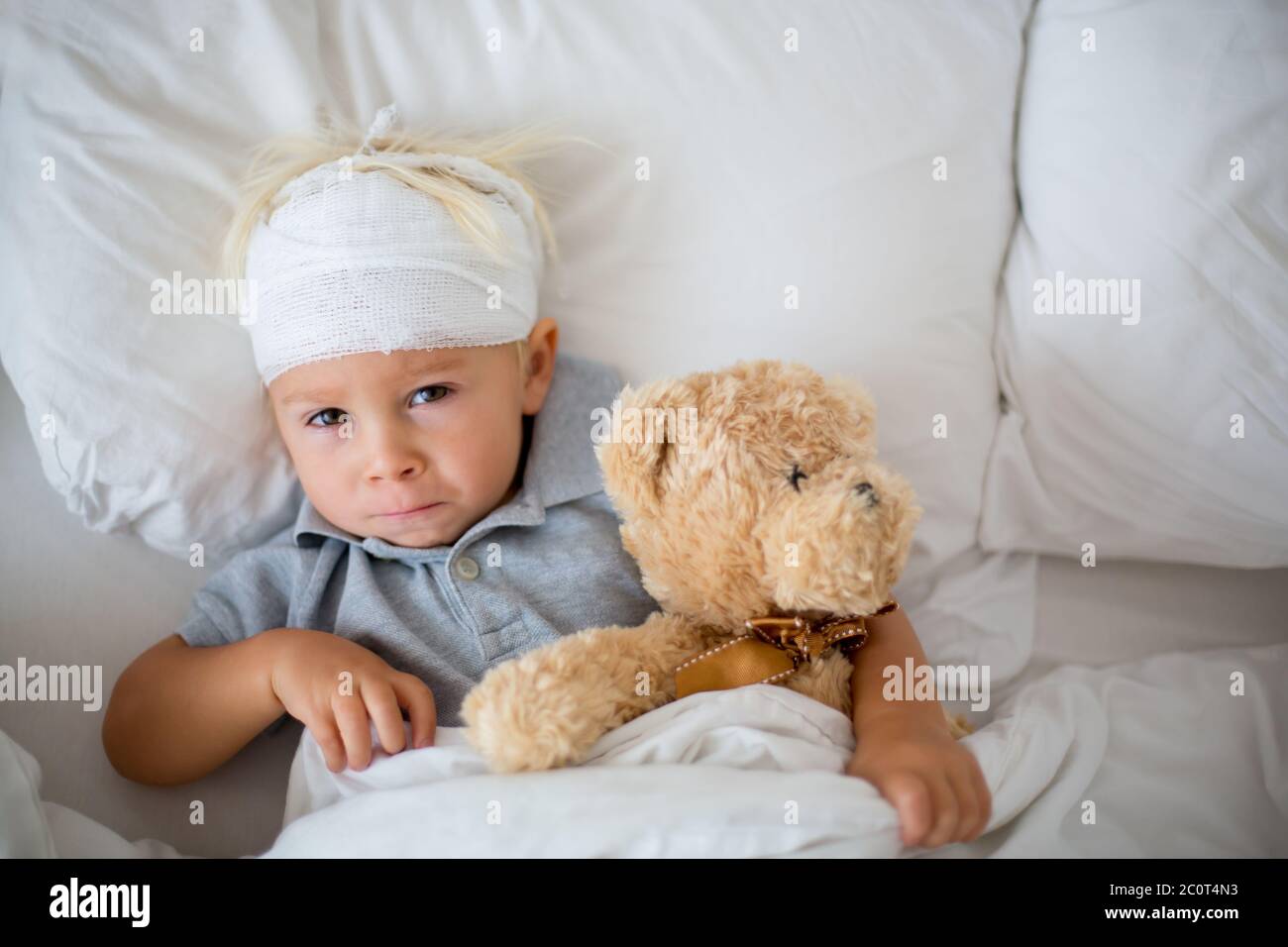 Little toddler boy with head injury, lying in bed, tired, sleeping
