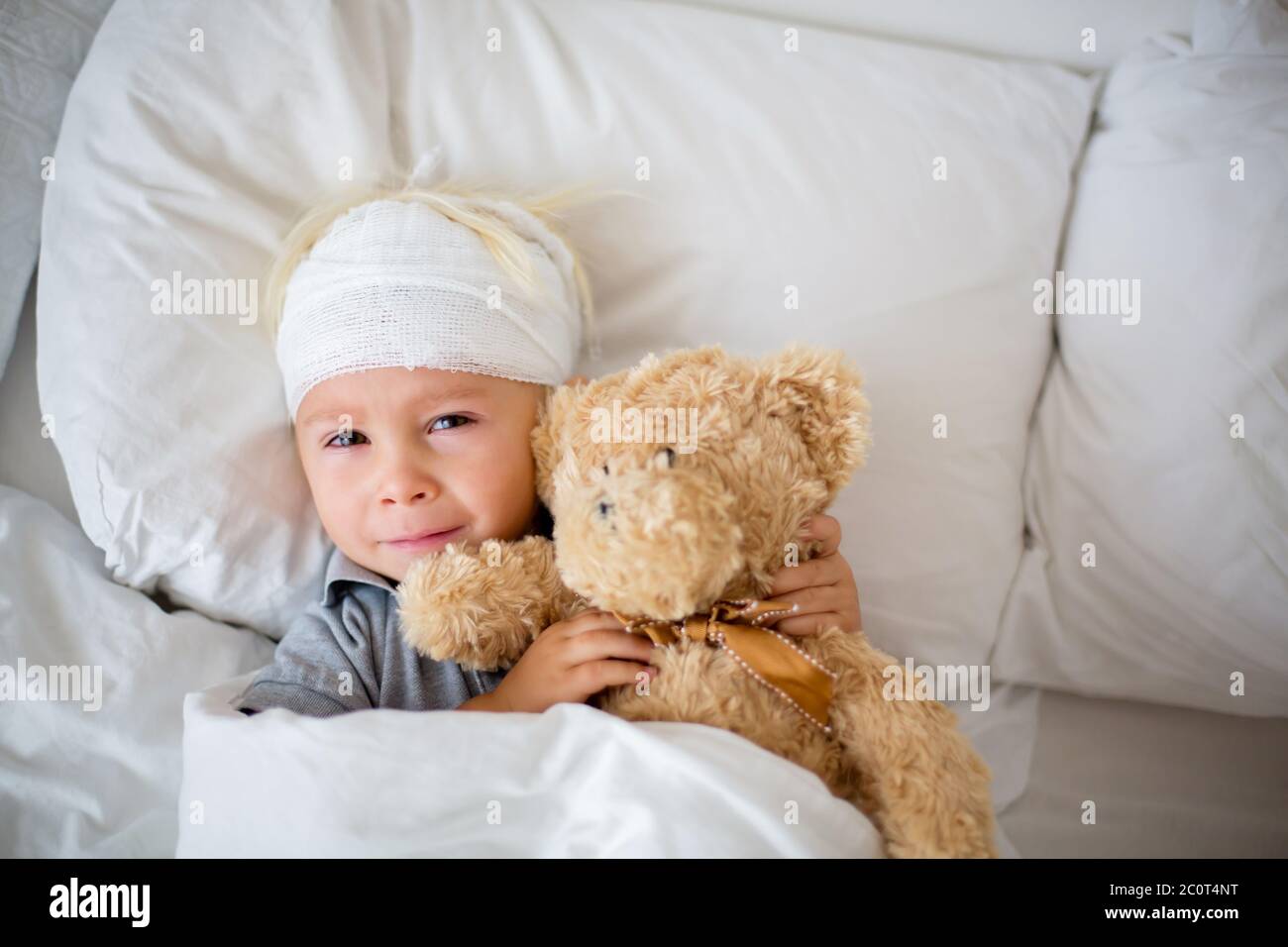 Little toddler boy with head injury, lying in bed, tired, sleeping