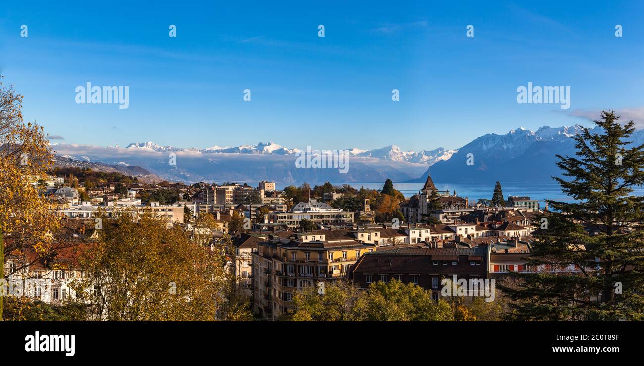 Aerial panorama view of Lausanne cityscape with snow covered French Alps and Lake Geneva (Lake Leman) in background on a sunny autumn day with blue sk Stock Photo