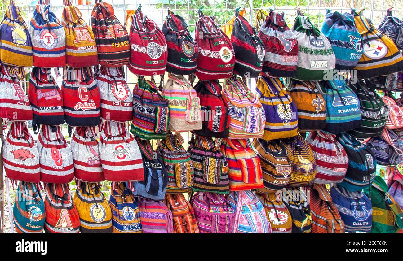 Backpacks monogrammed  with American tourists' favorite schools and teams on offer at a roadside stand in the village of Macario Gomez, Quintana Roo. Stock Photo