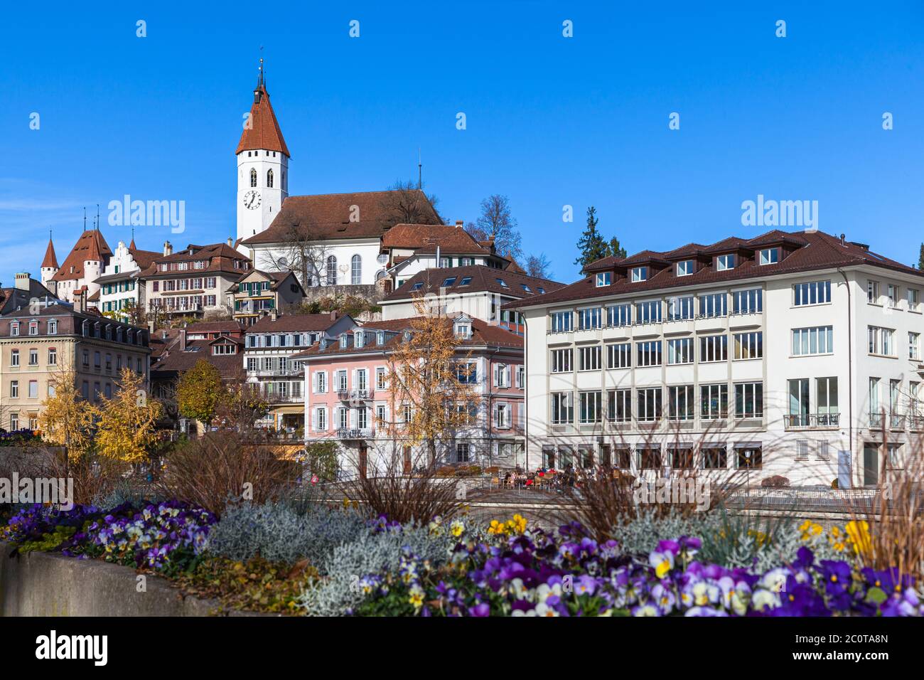 Beautiful panorama view of Thun old town from Aare river side on a sunny autumn day with Central Church, Thun Castle and blue sky in background, flowe Stock Photo