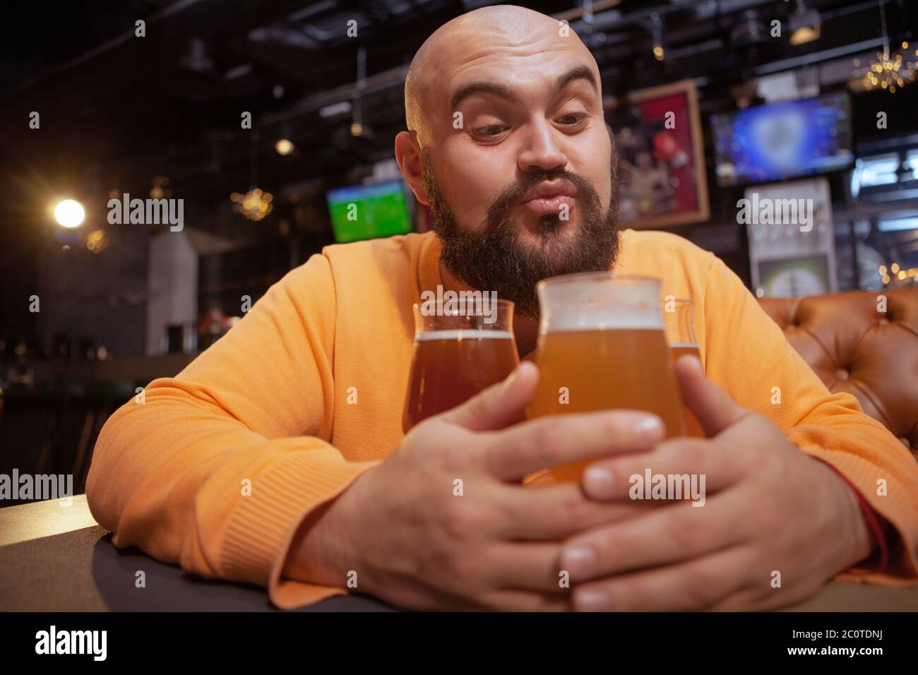 Funny bearded man blowing kisses towards his beer glasses, copy space. Alcohol love, craft beer concept Stock Photo