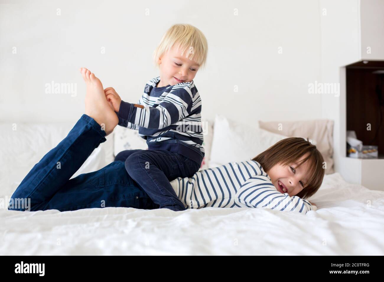 Children, brothers, playing at home, tickling feet laughing and smiling Stock Photo