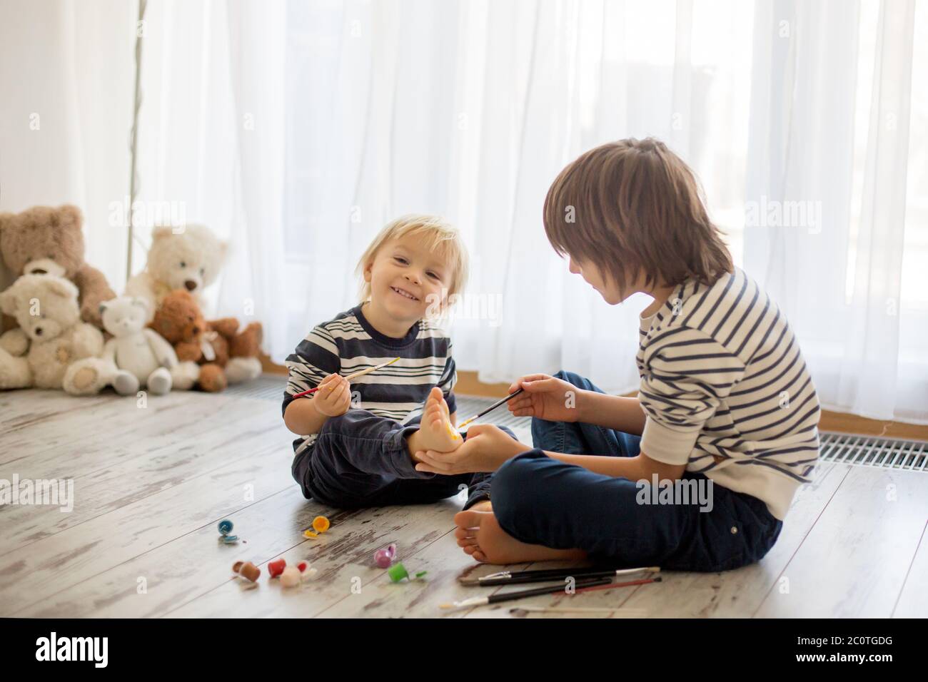 Brothers, playing at home, painting on their feet, tickling, laughing and smiling Stock Photo