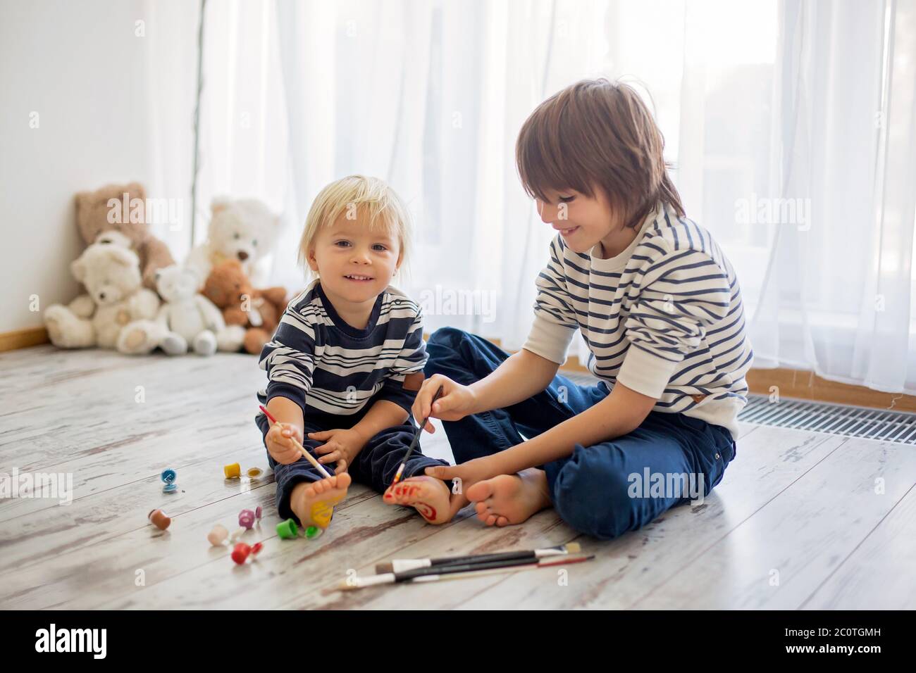 Brothers, playing at home, painting on their feet, tickling, laughing and smiling Stock Photo